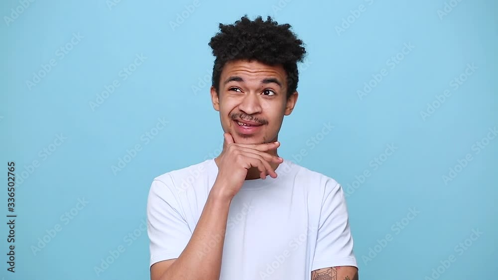Thinkful pensive sad unshaven african american young guy 20s in white t-shirt curly hair spreading hands without new idea isolated on blue background studio portrait. People emotions lifestyle concept