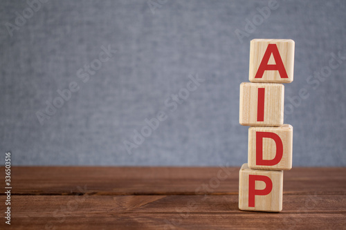 Abbreviation AIDP (Acute Inflammatory Demyelinating Polyradiculopathy) text acronym on wooden cubes on dark wooden backround. Medicine concept. photo