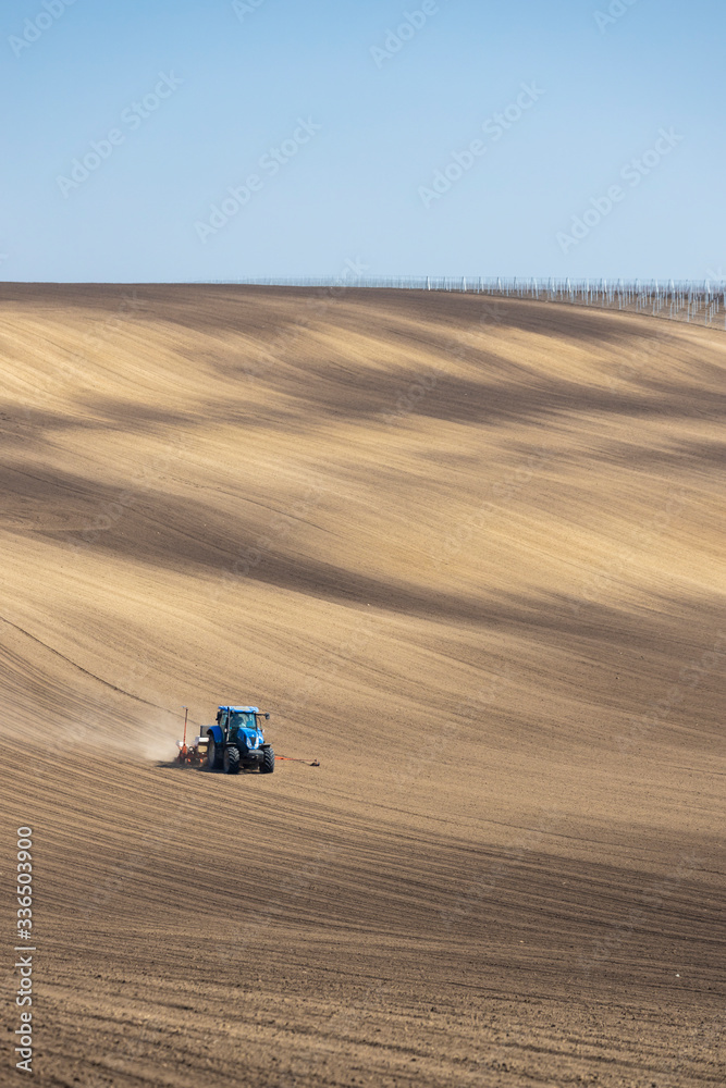 Tractor with seed drill in early spring landscape