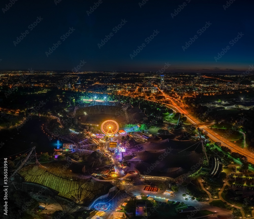 an impressive night view photo over Munich from the Olympic Tower at the ImPark festival at night with an illuminated ferris wheel.