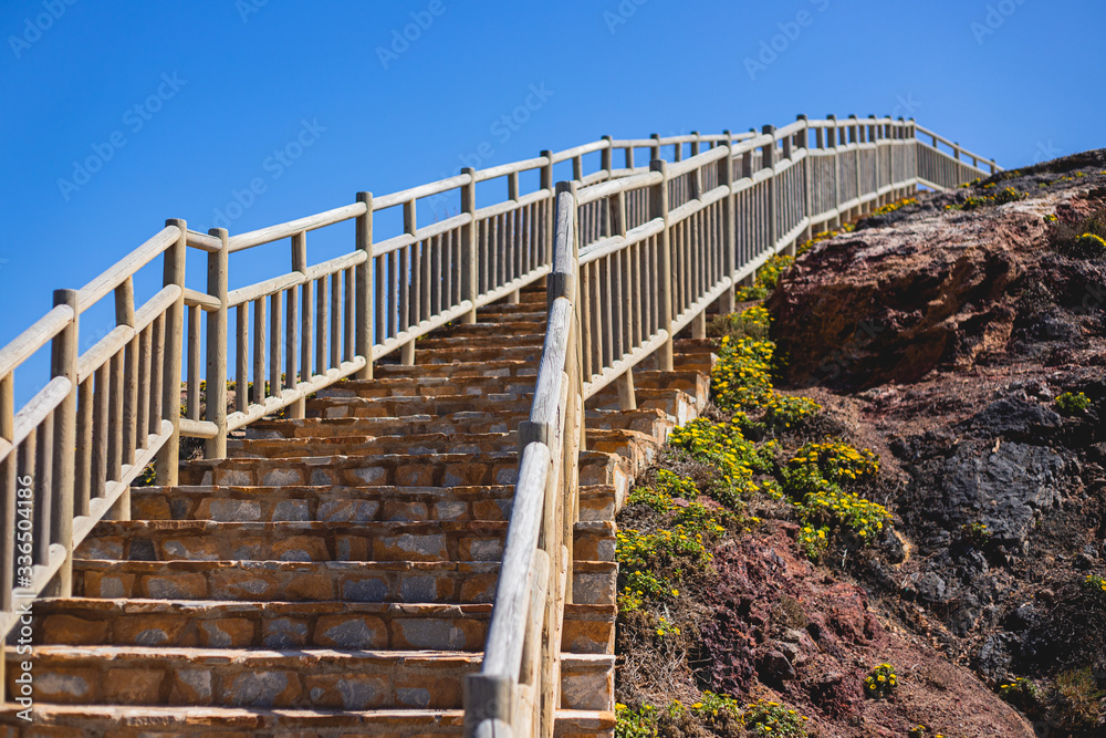Escalera exterior de piedra con valla de madera en la costa junto al mar
