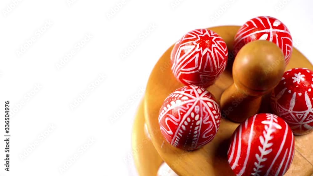 Red easter eggs with folk Ukrainian pattern lay and revolve on wooden stand for eggs which stand on white background. Top view. Ukrainian traditional eggs pisanka and krashanka. Red easter eggs with folk Ukrainian pattern lay and revolve on wooden stand for eggs which stand on white background. Top view. Ukrainian traditional eggs pisanka and krashanka.