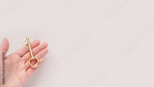 Gold key in woman hand on white background with copyspace. Stock photo.