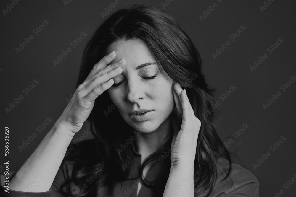 Bored mature woman with long hair having headache, studio portrait. Girl putting hands on head, isolated on grey background. Concept of problems and headache. Black and white Bored mature woman with long hair having headache, studio portrait. Girl putting hands on head, isolated on grey background. Concept of problems and headache. Black and white