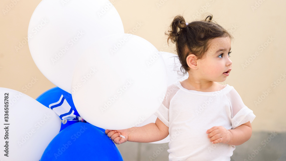 Beautiful small girl with blue and white balloons and Israel flag. Patriotic holiday Independence day Israel - Yom Ha'atzmaut concept. Banner. Beautiful small girl with blue and white balloons and Israel flag. Patriotic holiday Independence day Israel - Yom Ha'atzmaut concept. Banner.