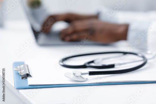 Stethoscope on medical chart over working with laptop doctor
