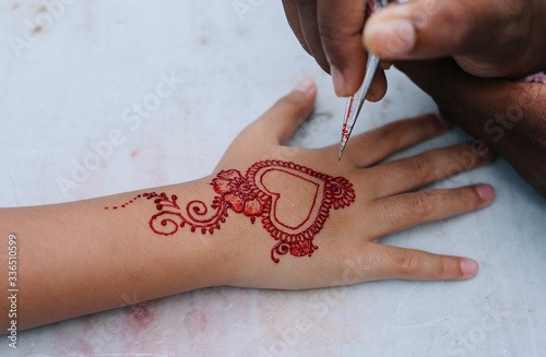 Image detail of henna being applied to kids hand by artist at street