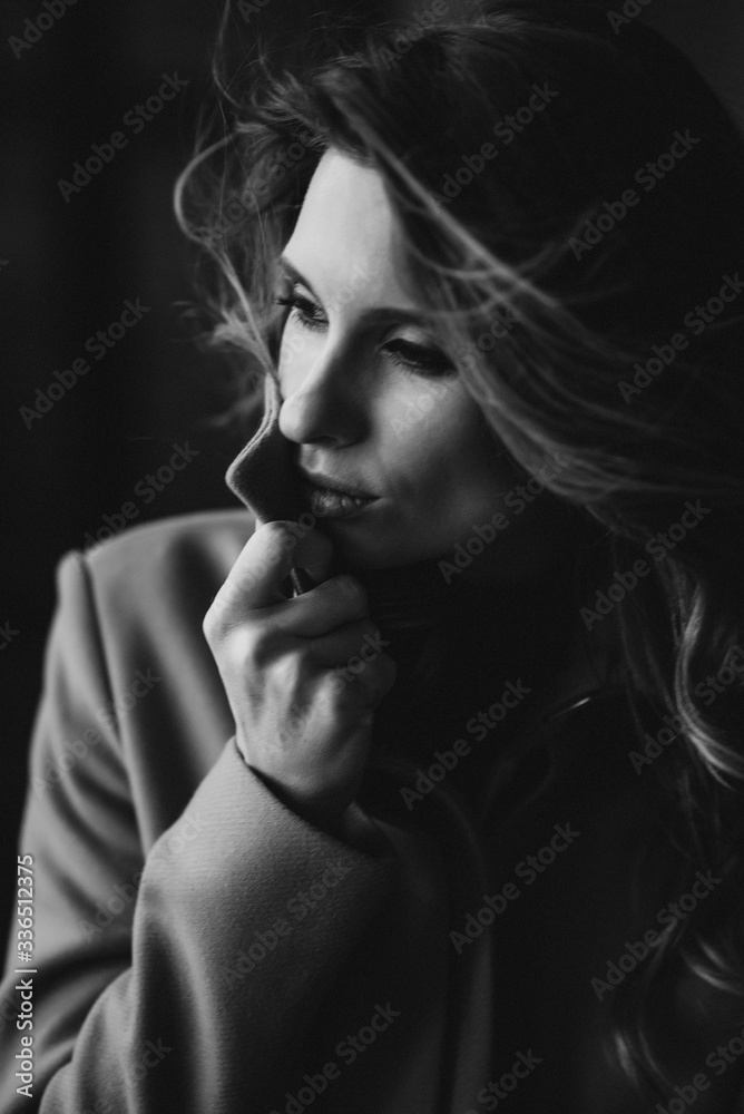 Beautiful sexy woman with curls and full lips in a coat in the style of a loft studio. Black and white art photo. Beauty and fashion. Soft selective focus. Beautiful sexy woman with curls and full lips in a coat in the style of a loft studio. Black and white art photo. Beauty and fashion. Soft selective focus.
