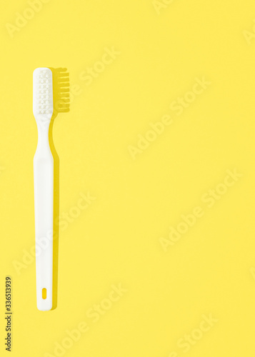 Classic toothbrush on yellow pastel background.