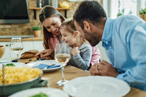 Young family having fun while talking at dining table.