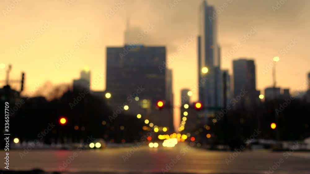 Blurred Chicago at night with cars passing thru intersection with lights on. Chicago cityscape from street level and busy intersection. Blurred Chicago at night with cars passing thru intersection with lights on. Chicago cityscape from street level and busy intersection.