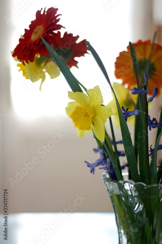 Crystal vase on a table with gerbera  hyacinth and daffodil flowers. Selective focus.