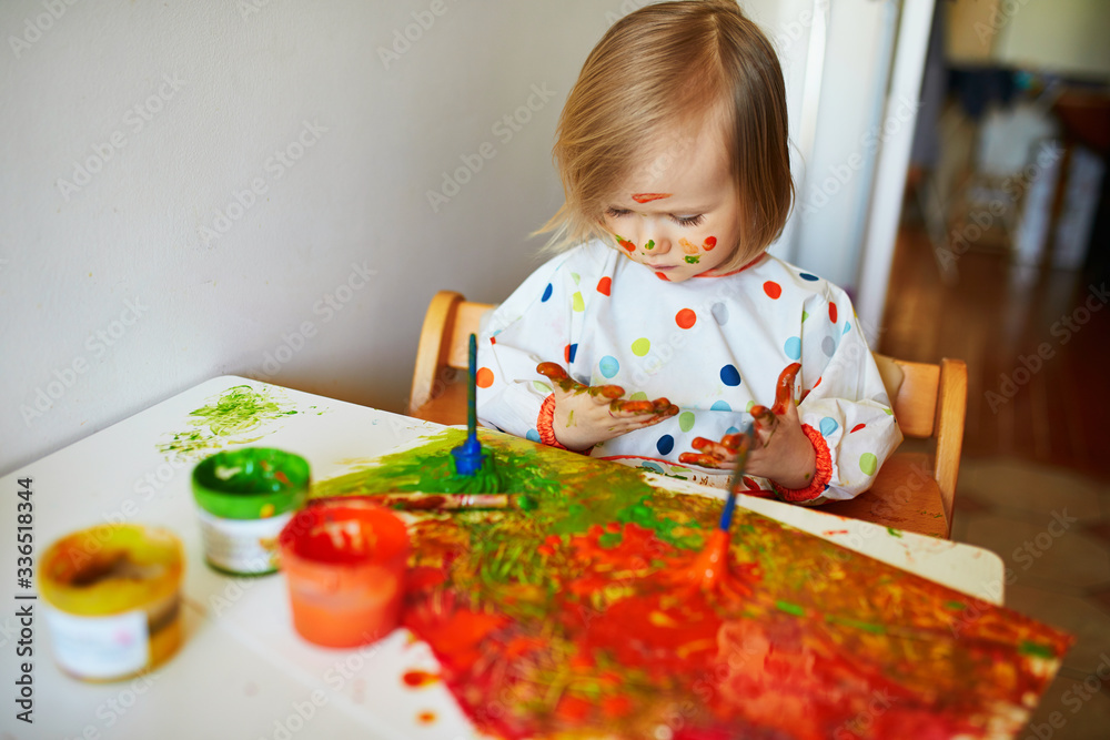 Adorable little girl painting with brushes and fingers Adorable little girl painting with brushes and fingers