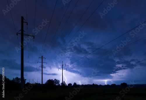 Silhouette of power lines on thunderstorm with lightnings background