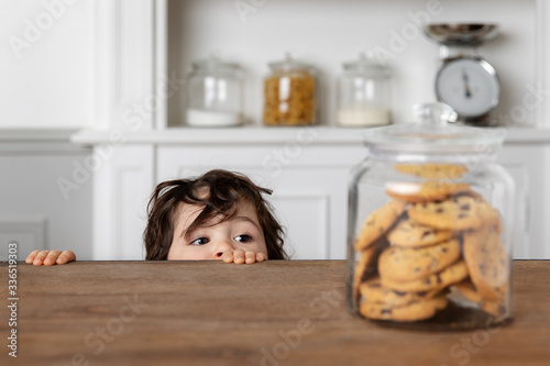 Toddler looking at cookie jar on kitchen table