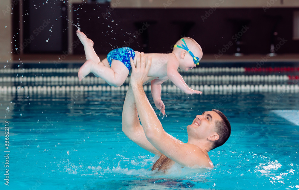 Father and son play in the pool. the father throws the son.