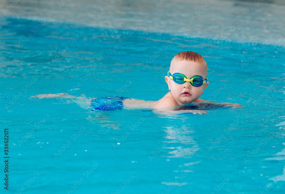 Naklejka premium Baby boy swims independently in the pool.
