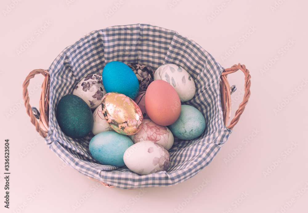 Wicker basket with colored Easter eggs on a light background Wicker basket with colored Easter eggs on a light background