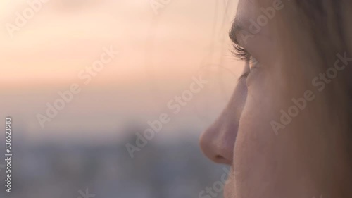 A woman looks out at urban city in the distance as day turns to night Golden Hour With Clouds 180fps
