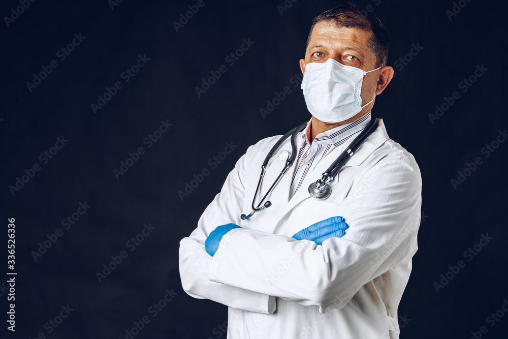 Elderly doctor with a medical face mask isolated on blue background. Close up. Elderly doctor with a medical face mask isolated on blue background. Close up.