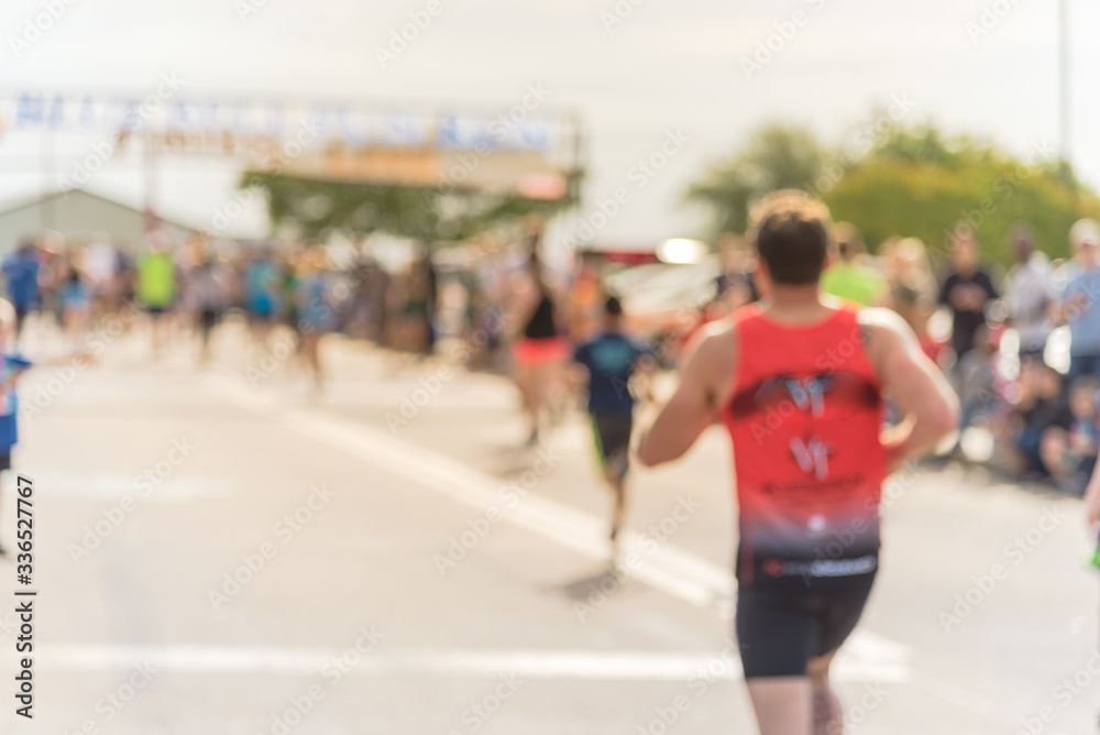 Blurry healthy man approaching finish line with crowded cheering at running event in Texas, USA