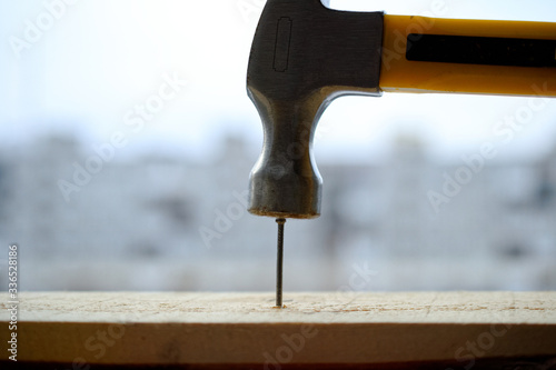 Photo A powerful hammer hammers a nail into a wooden board.
