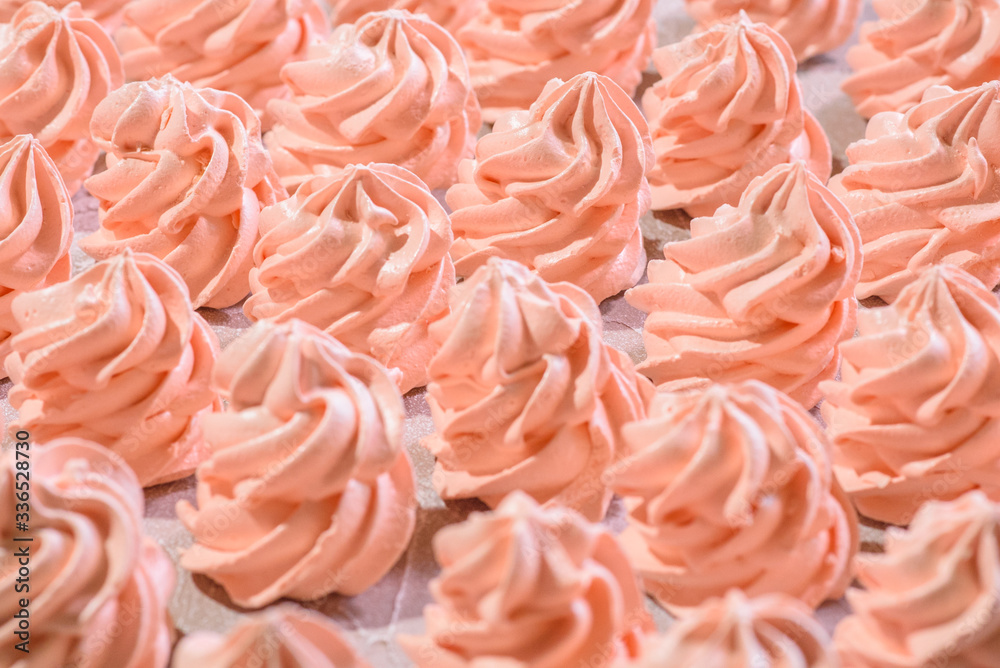 Delicious pink freshly made meringues lined up symmetrically on a concrete background. Pattern. Delicious pink freshly made meringues lined up symmetrically on a concrete background. Pattern.