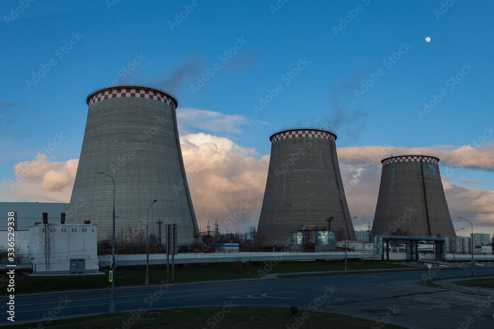 Three huge concrete pipes of a power plant in a row against a background of the evening sky