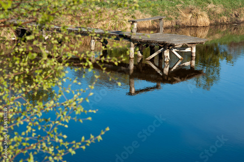 bllue water of pond with bridge with water reflection and young green spring ...