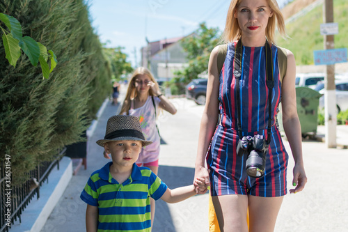 A little boy in a hat with a mom and a camera for a walk in the summer.