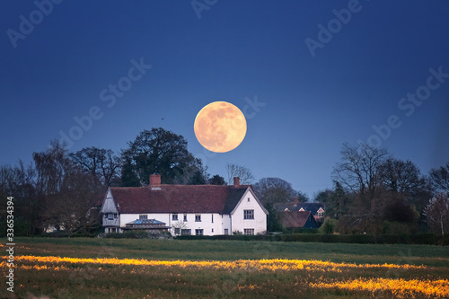 Pink Moon above a Suffolk farm white house in the English countryside