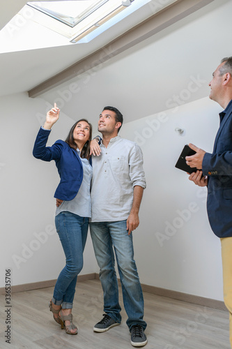 Happy couple visiting  a flat with a roof windows in an attic room
