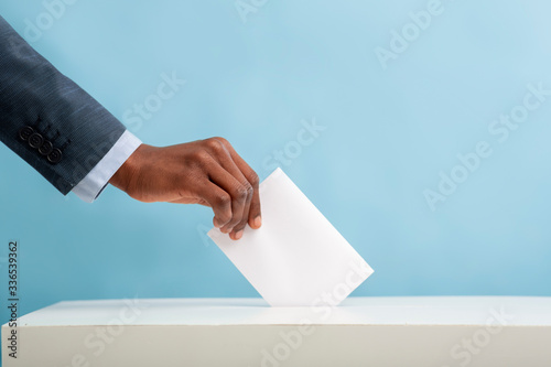 African american man putting an empty ballot in election box photo
