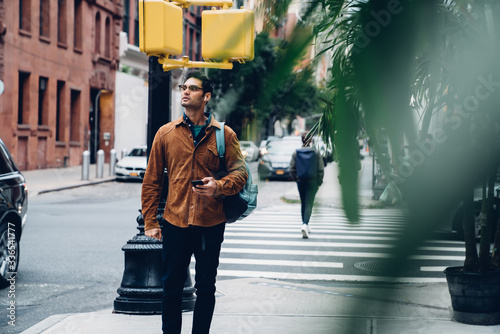 Canvas Print Ethnic young with phone strolling on street