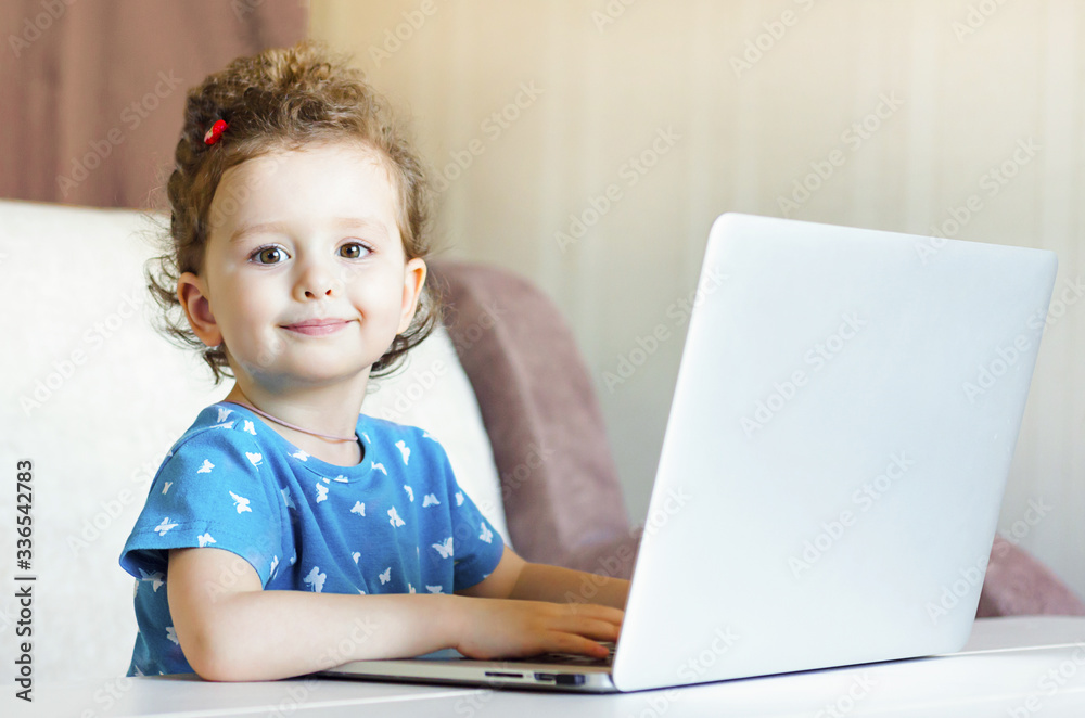 happy child is playing at the computer and smiling. little girl is studying remotely. online training. children and internet. Distance learning online education. copy space happy child is playing at the computer and smiling. little girl is studying remotely. online training. children and internet. Distance learning online education. copy space