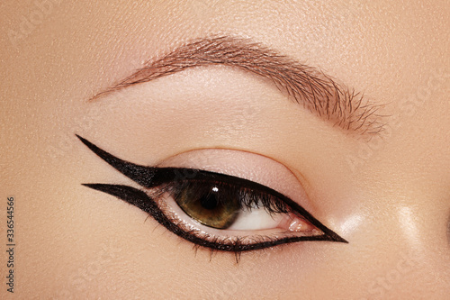 Beautiful Macro of Female Eye with Fashion Black Eyeliner Makeup. Perfect graphic Liner shape. Cosmetics and make-up photo