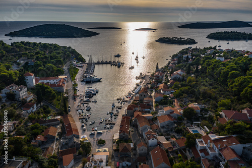 Croatia, Maslinica, 15 September 2019: Drone view point on moored in an equal row sailboats at sunset, participant of a sailing regatta, people have a rest after racing day, azure water, pier © Vladimir Drozdin