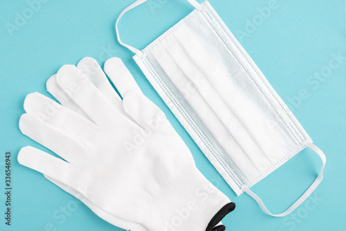 Prevention and protection against the spread of viruses and diseases. White antibacterial medical mask and protective gloves on a blue background