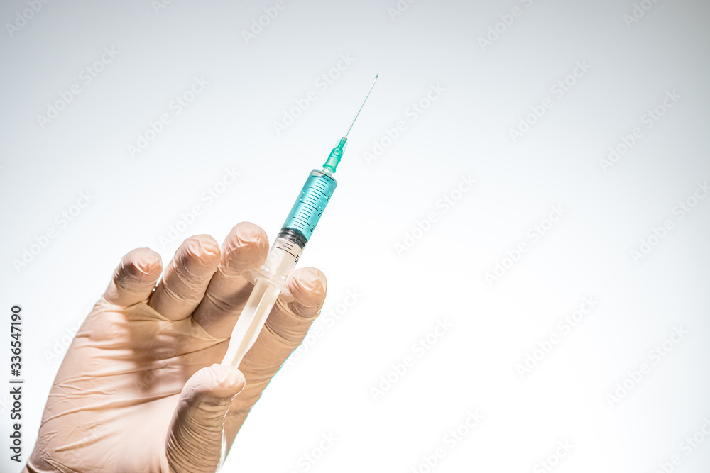 Hand wearing latex glove holding syringe with a medicine on white background