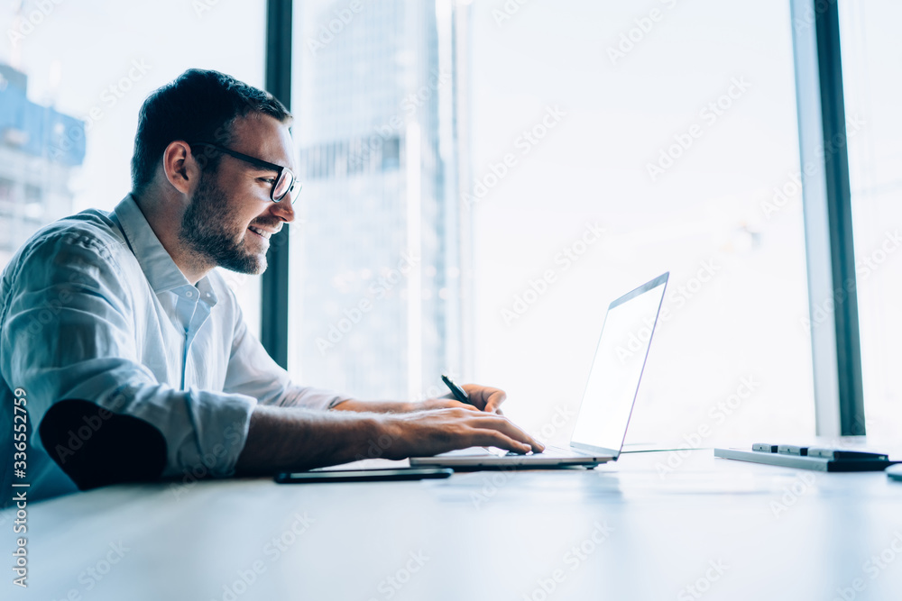 Smiling man using laptop in office Smiling man using laptop in office