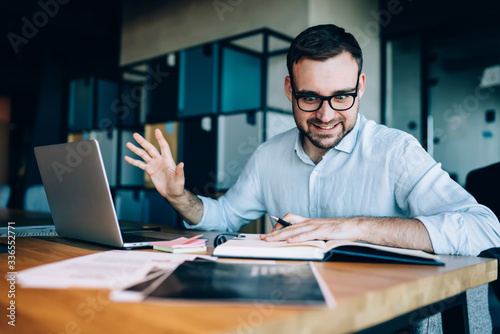 Angry male investor in optical eyewear reading report information in textbook and feeling stress with deadline job for solving exchange problem, Caucasian businessman having overtime at desktop