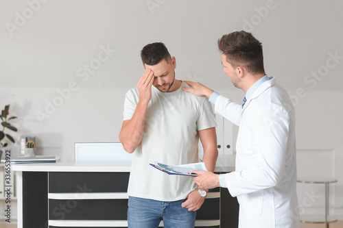 Male doctor calming sad pat...