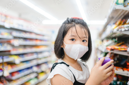 Coronavirus Covid-19 concept.Little chinese girl wearing face mask protect from virus and show thumb up gesture for good.Coronavirus outbreak in supermarket coronavirus and pandemic virus symptoms.