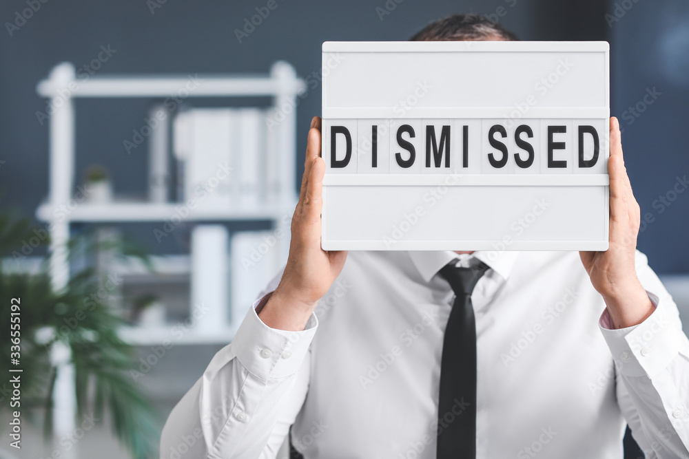 Man holding board with text DISMISSED in office Man holding board with text DISMISSED in office