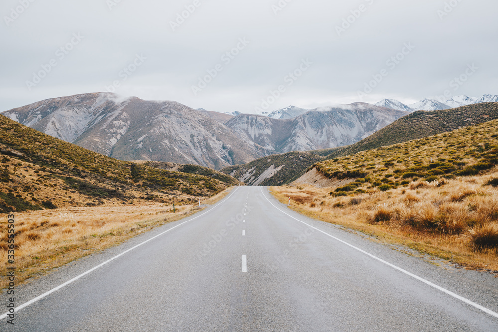 Empty road leading to snow capped mountains