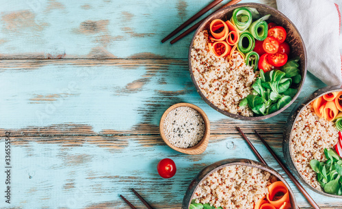Vegan Buddha bowl. Healthy meal quinoa, tomato, cucumber, carrot, radish, corn salad in coconut bowls on blue rustic background.
