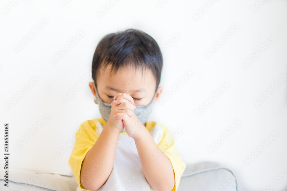Little Chinese toddler boy wearing face mask for Covid-19 coronavirus.Prayer kid boy worship to GOD at home in sunday service.Church online.Coronavirus pandemic.Hand praying for thank GOD.Copy space. Little Chinese toddler boy wearing face mask for Covid-19 coronavirus.Prayer kid boy worship to GOD at home in sunday service.Church online.Coronavirus pandemic.Hand praying for thank GOD.Copy space.