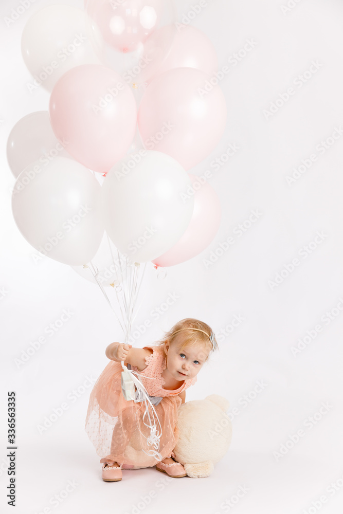 Little cute girl holds branch of balloons and large Teddy bear enjoy festive birthday event wear pink pastel summer dress isolated on a white background. Little cute girl holds branch of balloons and large Teddy bear enjoy festive birthday event wear pink pastel summer dress isolated on a white background.