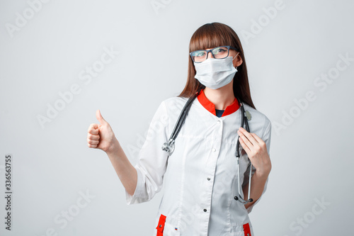 Young doctor in a coat and mask on a white background