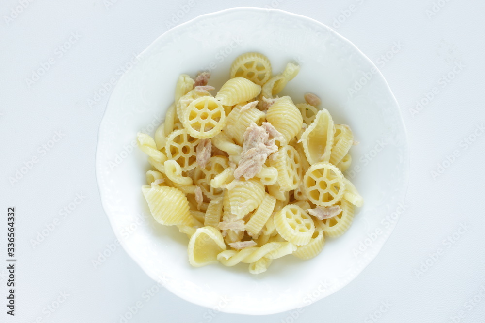Prepared pasta and tuna salad in white bowl on white background